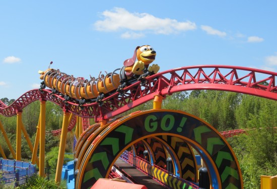 Roller coaster shaped like Slinky Dog rides 20+ feet in the air over a walkway that looks like a video game racetrack. It has circular arches; the front one says "GO!"