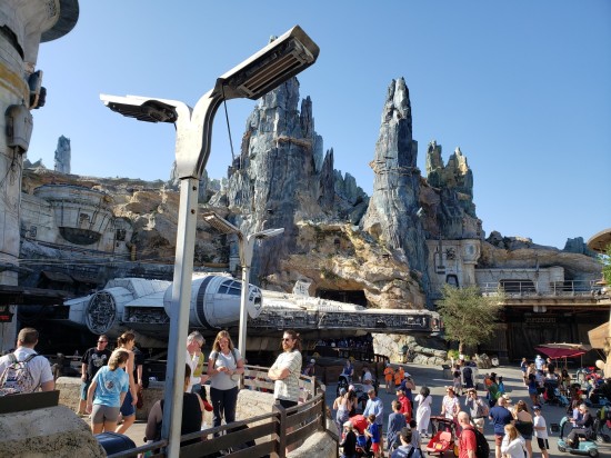 Millennium Falcon parked in front of jagged stone peaks dozens of feet tall. Crowds of tourists spoil the sci-fi of it all.