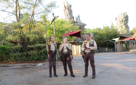 Three Disney World employees in Star Wars sequel costumes, standing on a park path and chatting.