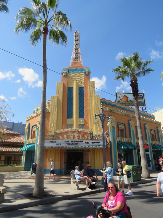 Yellow Art Deco theater with marquee promising Pixar, toys, treasures, "and beyond!"