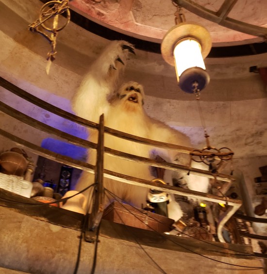 Lifelike Wampa statue on a second floor with railing in front of it. Rocklike walls.