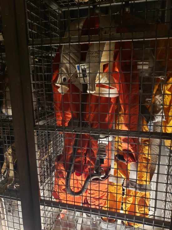 Orange X-Wing flight suit hanging in a cage.
