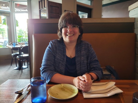 My wife nicely dressed in a restaurant booth and looking half her age in a dignified way.
