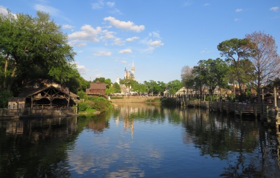 Pretty reflecting lagoon in late afternoon, trees around its shores. Cinderella Castle is on the horizon.