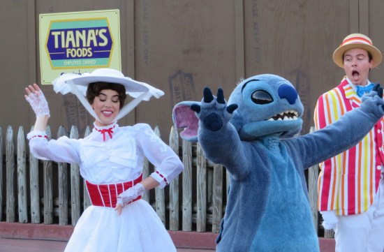 Disney World parade cast members: Mary Poppins and Stitch, dancing. Mary's eyes are closed. Bert the chimney sweep is nearly offscreen, aghast at something.