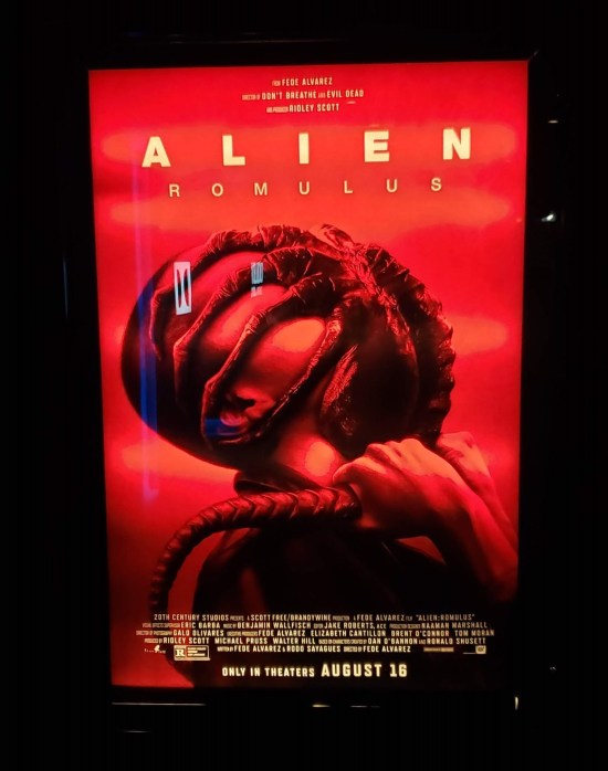 Red-and-black poster with a xenomorph face-hugger attached to a buzz-cut Asian actress.
