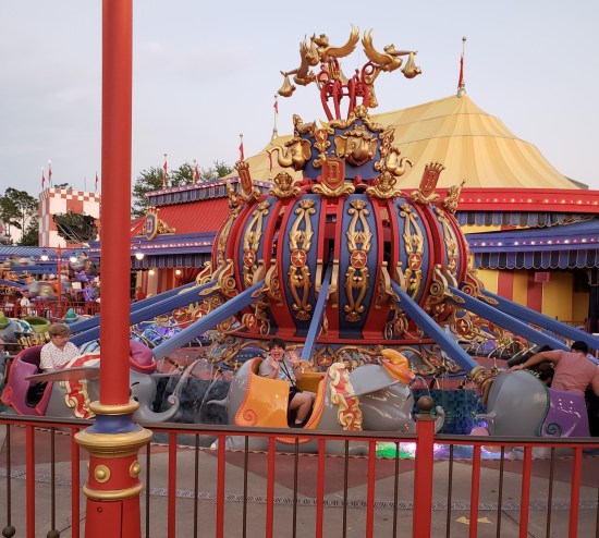 Anne sitting in the motionless red and yellow ride, doing jazz hands while waiting to start.