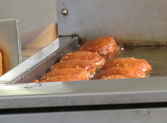 Eight biscuits frying in a restaurant vat.