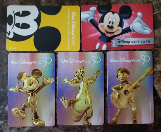 Five Disney World gift cards, three of which could double as hotel room keys and contain 50th-anniversary images of gold statues of Mickey Mouse, Figment, and Miguel from "Coco".