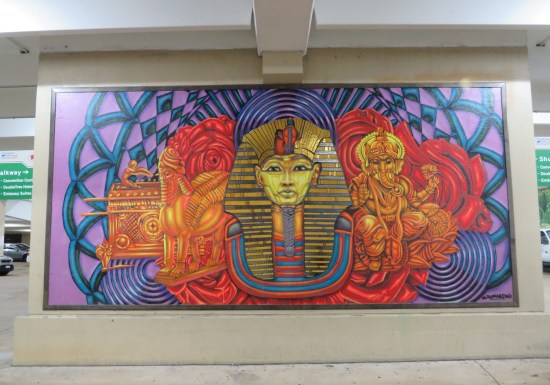Garage mural with shiny pharaoh headgear, yellow Ganesh, an Ark of the Covenant and a weird hieroglyphic doggie statue or something, all set on a blue-and-purple fractal backdrop.