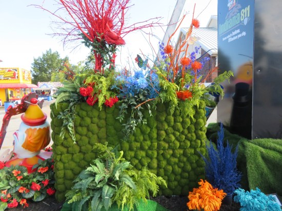 Lots of flowers behind arch, including spherical greenery in a cubic lattice.
