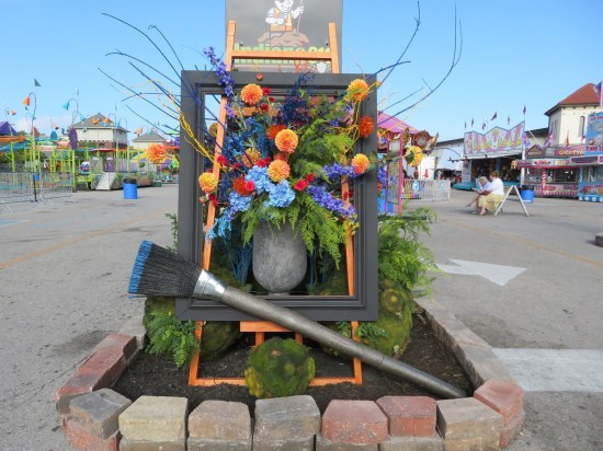 Behind the arch, a bouquet of flowers in a vase sits inside a picture frame with a large paintbrush lying in front of it.