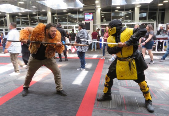 cosplay: Kraven the Hunter with a spear, standing off against Scorpion from Mortal Kombat.