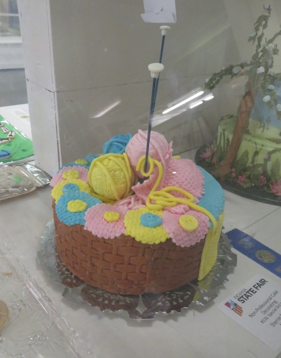 Cake with icing shaped like balls of yarn on top and fancy latticework all around.