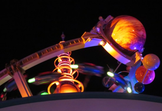Planets and imitation observatory parts on the roof of the PeopleMover tracks at night.