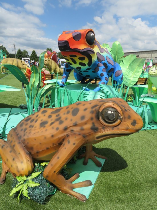Two large poison frog statues, one brownish and one red, yellow and blue.