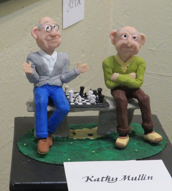 Two stop-motion grandpa puppets fuming at a chess board.