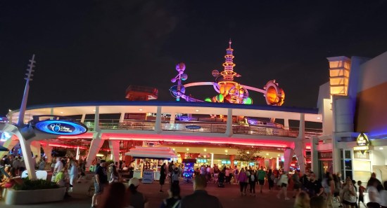 Theme park stores and rides shaped like 1960s ideas of the future, but at nighttime so they're all lit up prettily.