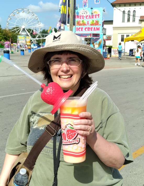 Anne smiles while holding up a 32-ounce plastic cup that says "Strawberry" on it under a picture of a strawberry.