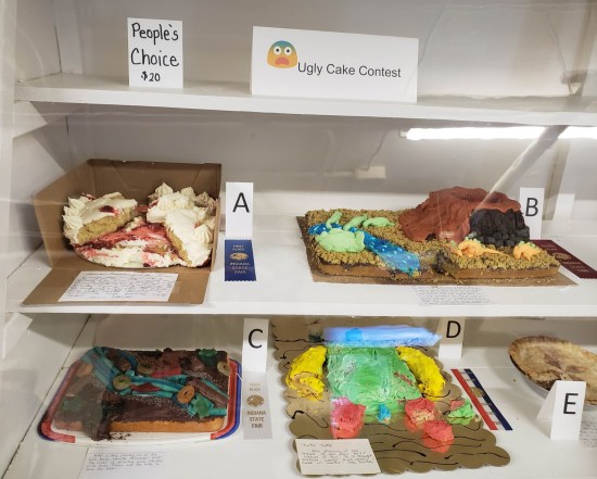 Four wrecked cakes in a white vitrine, and an apple pie.