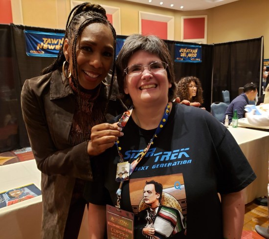 Anne posing with Dawnn Lewis, who's holding up the Captain Freeman pin on Anne's lanyard.