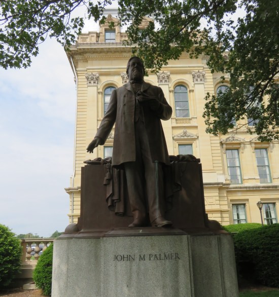 Statue of John M. Palmer on a pedestal, standing in front of another pedestal with a wrapped flag on it?