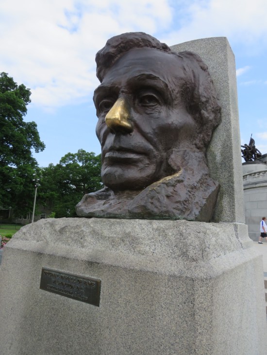 giant Lincoln statue head on a stone base. It's all gray except his nose is bright bronze.