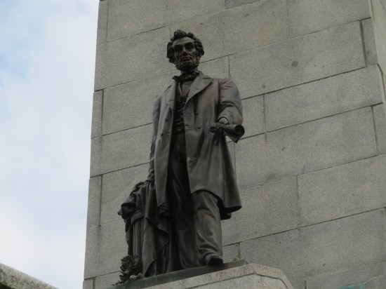 Worms-eye view of a Lincoln statue holding out a rolled-up copy of the Emancipation Proclamation.