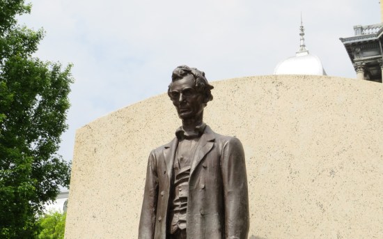 Closeup of top half of same Lincoln statue. Daytime outside, light blue sky.