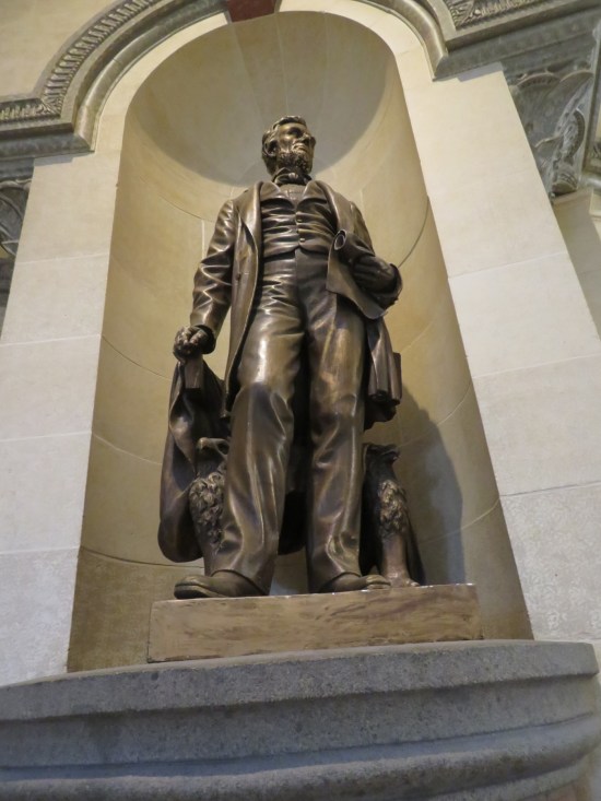 Lincoln statue in an alcove, dangling his suit jacket in one hand and gripping a scroll in the other.