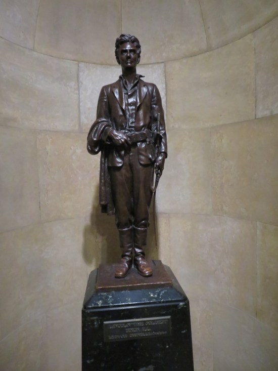 Statue of young Lincoln with a sheathed sword and his jacket draped on his arm.