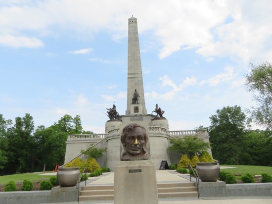 Tall white obelisk atop dual staircases with statues out front, including a giant Lincoln head.