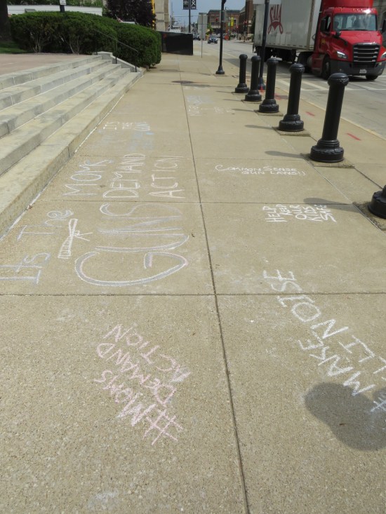 Sidewalks in front of the capitol covered in chalk messages such as "Make Some Illinoise", "Help Keep Our Kids Safe", and the Moms Demand Action hashtag.