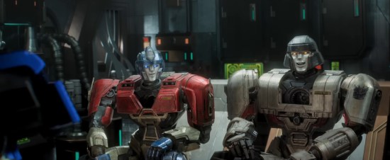 Young Optimus Prime and Megatron sitting on a couch and smiling.