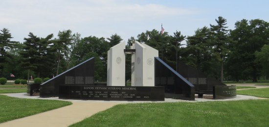 Four white columns with angled tops surrounded by short black marble walls AND taller black trapezoidal columns covered in fallen soldiers' names.