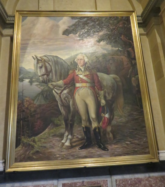 Cockeyed shot of a painting of General George Washington standing by his horse, holding its rein with a gloved hand. Background is river and woods.