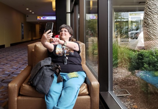 Photo of Anne photographing herself in a Hyatt lounge chair in a hallway next to the front windows.