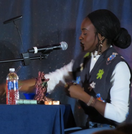 Celia Rose Gooding with an ornate dice tower shaped like writhing dragons.