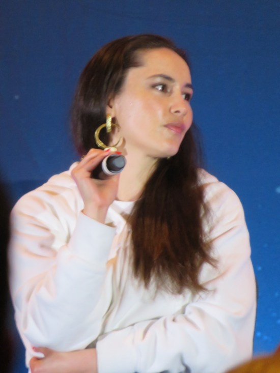 Christina Chong on stage with mic, turned and listening.