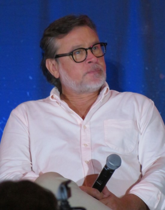 Connor Trinneer sitting on stage with mic, wearing glasses and white shirt.