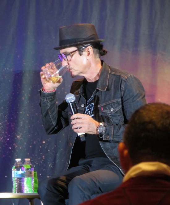 Dominic Keating drinking, also in hat.