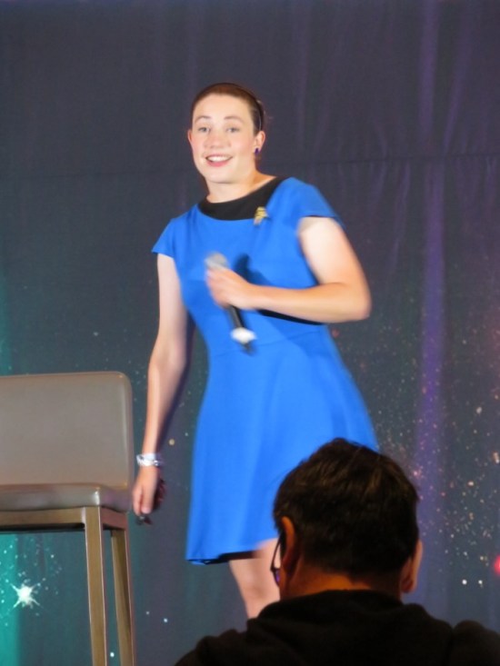 Katie Nickolaou on stage in blue Original Series uniform.