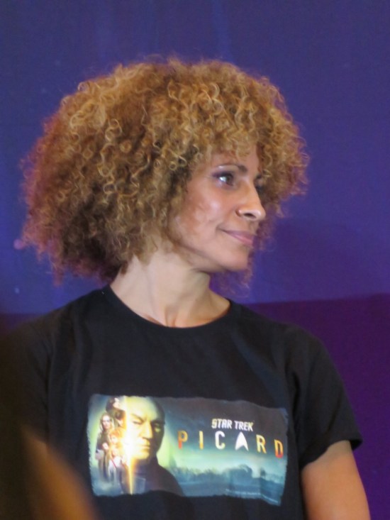 Michelle Hurd on stage, turned and listening.