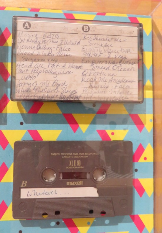 A cassette tape hand-labeled "Whatever" and a cassette case with random songs written on the sleeve.