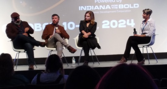 Stage at the front of a movie theater, with Heartland logo projected on screen. Refer to caption for people.