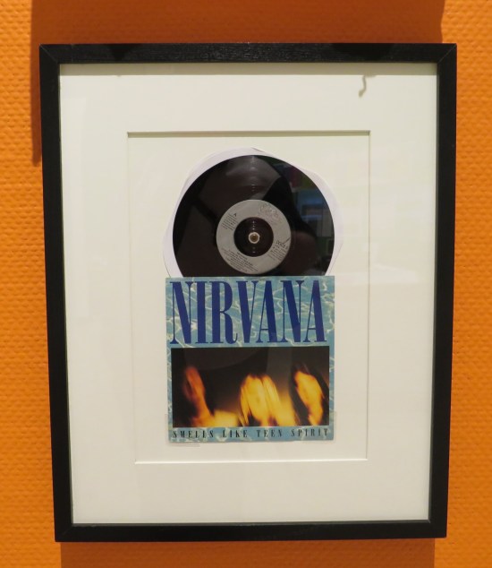 An original 45 of Nirvana's "Smells Like Teen Spirit" framed and hung on a wall.