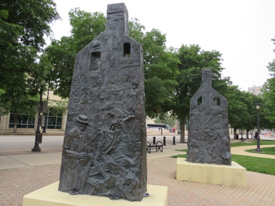 Two outdoor statues of chimneys with Black figures carved into them.