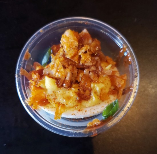 Overhead view of a fancy deviled egg in a tiny, translucent plastic cup.