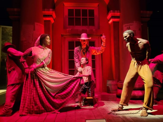 Life-sized early-1800s diorama of slavers dragging off a Black husband, wife and son in different directions.