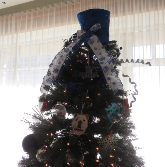 Christmas tree decorated with blue top hat topper, bulldog mascot face and game console controllers.